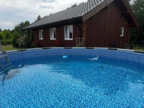 a large blue swimming pool in front of a house at Brzozowa Aleja in Radawa