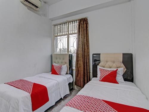 2 Betten mit roter und weißer Bettwäsche in einem Zimmer in der Unterkunft OYO 92746 Wisma 35 
