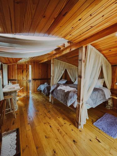 two beds in a room with wooden ceilings at Cabanas Avencal Frutas in Urubici