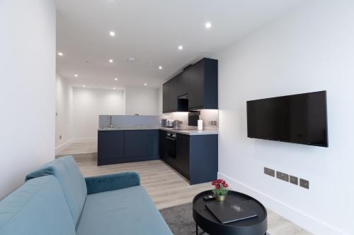 a living room with a blue couch and a kitchen at Stratford Apartments in London