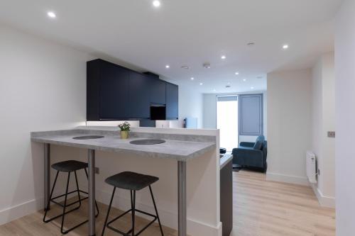 a kitchen with a counter and two stools at Stratford Apartments in London