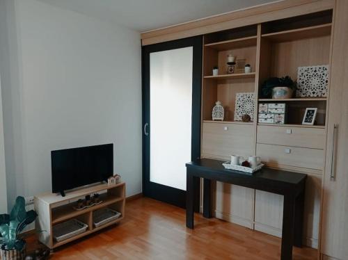 a living room with a table and a television at Acogedor apartamento con piscina y garaje in Huesca