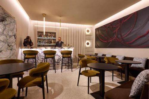 a man standing in a restaurant with tables and chairs at Borghese Contemporary Hotel in Rome