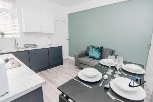 a kitchen with a table with plates and wine glasses at Balby Casa king beds parking workspace wifi corporates pets in Balby