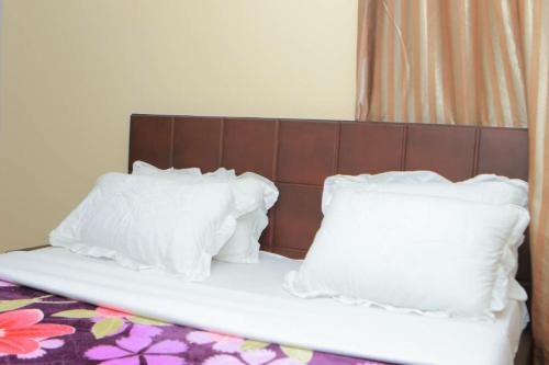a bed with white pillows on top of it at Alice Gardens & Campsite in Entebbe