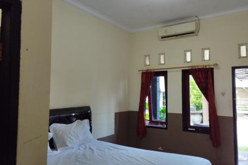 1 dormitorio con 1 cama y 2 ventanas en OYO 92756 Kos Moncok en Tjakranegara