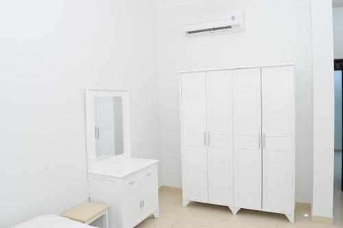 a white bedroom with a white cabinet and a mirror at RED-36 - Al Mareekhy Villas in Salalah