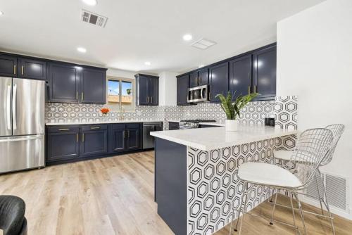 a kitchen with black cabinets and a kitchen island with chairs at Acacia Retreat by Rather Be Properties in Palm Springs