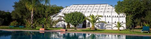 un grande edificio bianco con una piscina di fronte di Las Palmeras Guest House a Marrakech