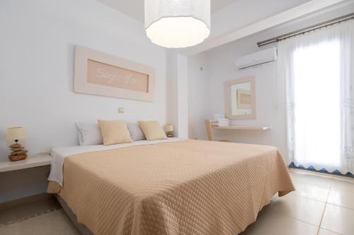 a white bedroom with a bed with a blanket at Villa Virginia in Ambelas