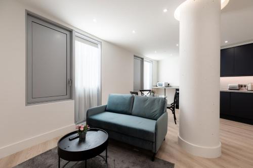 a living room with a blue chair and a table at StayInn Stratford in London