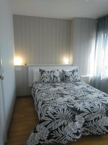 - une chambre avec un lit et une couverture noire et blanche dans l'établissement Estudio. Sada, A Coruña., à Sada