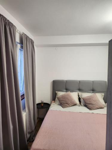 a bedroom with a bed with a pink blanket and a window at Studio Anka in Pakoštane