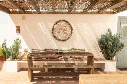 a bench in a patio with a wreath on the wall at Vida na Vila in Vila Nova de Milfontes