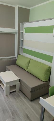 a room with a bed with a green pillow and a table at Cinema House Single & Double Rooms & Studio Apartments in Pula