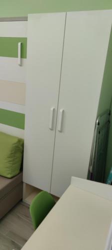 a room with a white cabinet and a green chair at Cinema House Single & Double Rooms & Studio Apartments in Pula