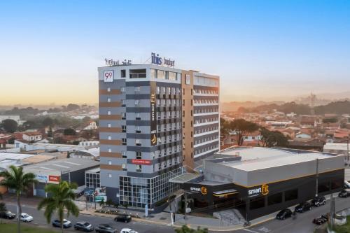 a tall building in a city with a parking lot at ibis budget Pindamonhangaba in Pindamonhangaba