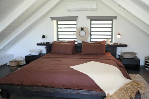 a large bed in a room with two windows at THE VILLA BY THE SEA Nouvelle-Caledonie in Mont-Dore
