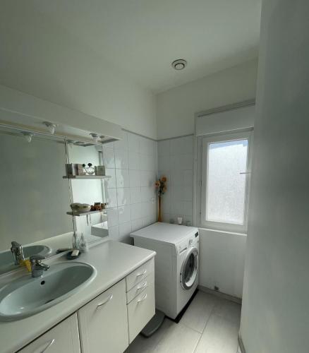 une salle de bain blanche avec une machine à laver et un lavabo dans l'établissement Appt Pontaillac Vue Océan, à Royan