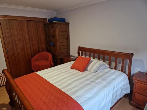 インバネスにある2 craiglea Croft Craigton North Kessockのベッドルーム1室(ベッド1台、オレンジ色の枕、椅子付)