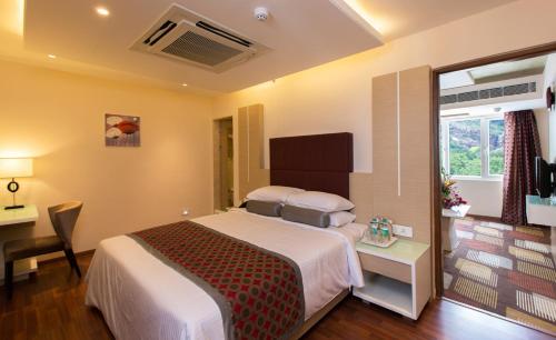 a bedroom with a bed and a desk and a window at Pai Viceroy in Tirupati