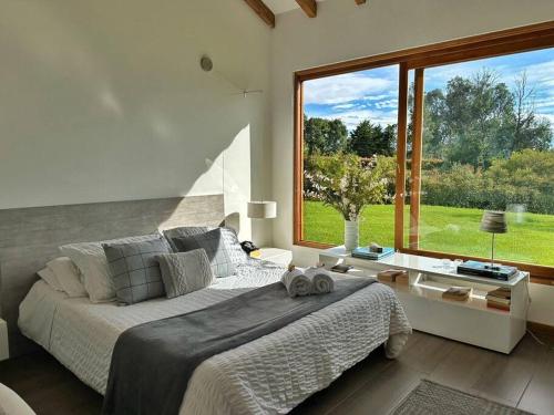 een slaapkamer met een groot bed en een groot raam bij Casa Araní - Vista espectacular y mucho jardín in Villa de Leyva