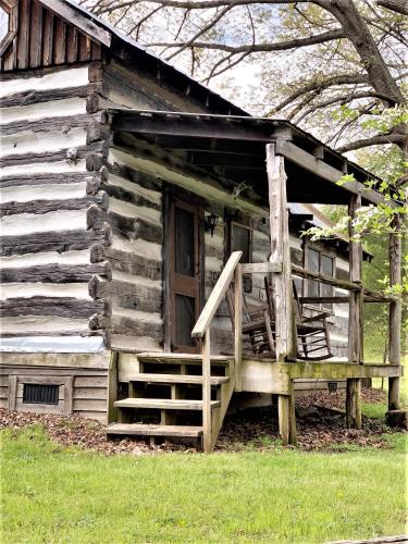 an old log cabin with a porch and a door at Heartstone Country Retreat in Buena Vista