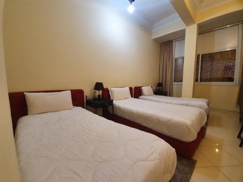 Bou ArfaにあるHotel Acharkのベッド2台と窓が備わるホテルルームです。