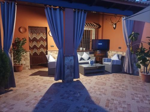 a living room with blue curtains and a tv at Casa El Albero (Torcal-Caminito del Rey) in La Joya