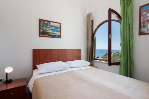 a bedroom with a bed and a window with the ocean at Apartments Delfin in Krk