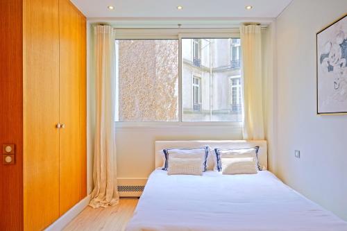 sypialnia z łóżkiem i oknem w obiekcie Avenue Montaigne - Prestigieux 2BR w Paryżu