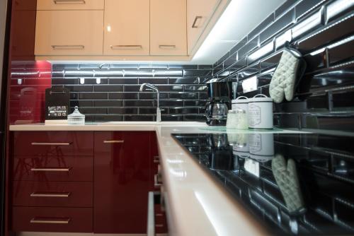 a kitchen with red cabinets and black tiles at Vonitsa Luxury Apartments in Vonitsa