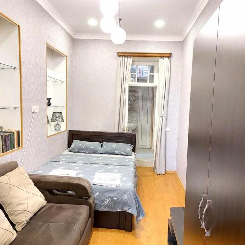 Un dormitorio pequeño con una cama y un sofá. en Dodo-Inga's Apartment, en Tiflis