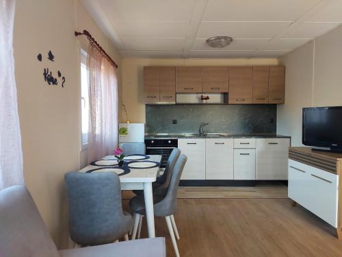 uma pequena cozinha com uma mesa branca e cadeiras em Къщички Sunrise em Tsarevo