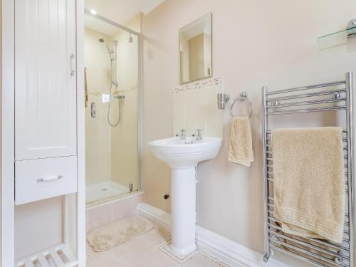 a white bathroom with a sink and a shower at Chestnut House in Bridgend