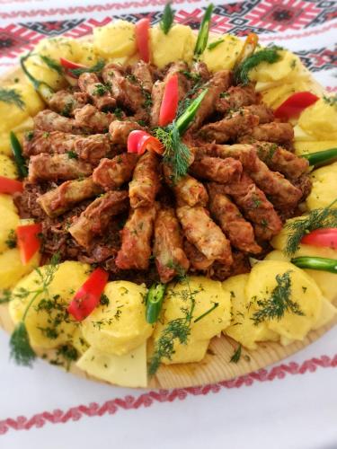 a plate of food with meat and potatoes at Pensiune Runcu Stone in Runcu