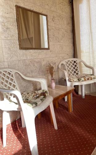 2 sillas blancas, mesa y espejo en Tamimi Home, en Hebron
