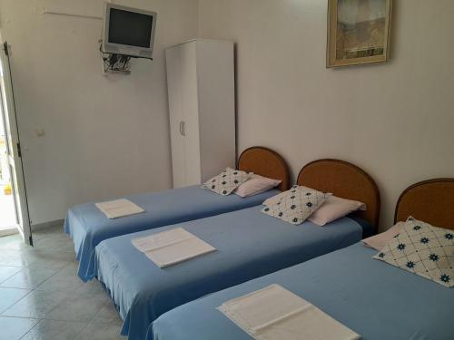 een kamer met twee blauwe bedden en een televisie bij Guest House Oroshi in Ulcinj