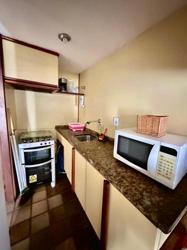 a small kitchen with a microwave and a stove at Ondina Apart Hotel Residences in Salvador