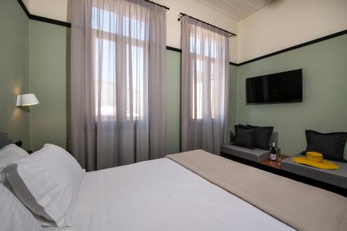 a bedroom with a white bed and a tv at Mosaic Venetian Harbour Suites in Chania Town