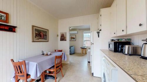 uma cozinha com uma mesa e algumas cadeiras e um balcão em Manoir Belle Plage em Carleton sur Mer