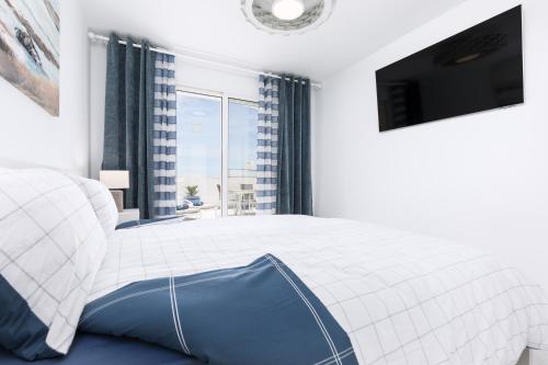 a white bedroom with a large bed and a tv at Casa Birke in Costa Calma