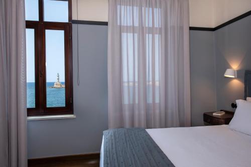 a bedroom with a bed and a window with a lighthouse at Mosaic Venetian Harbour Suites in Chania Town