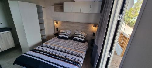 a small bedroom with a bed with a wooden headboard at Mobil Home Neuf Vue mer in Saint-Raphaël