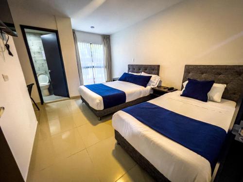a hotel room with two beds with blue pillows at Hotel Boutique Veracruz termales in Santa Rosa de Cabal