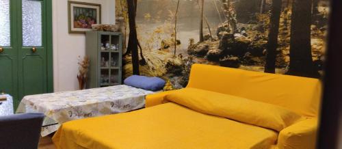 un sofá amarillo en una habitación con una pintura en Dal corso al mare, en Spadafora