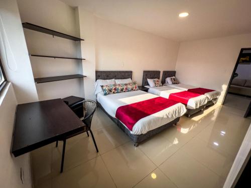 two beds in a room with a table and a desk at Hotel Boutique Veracruz termales in Santa Rosa de Cabal