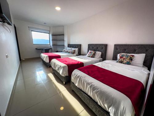 a hotel room with three beds and a window at Hotel Boutique Veracruz termales in Santa Rosa de Cabal