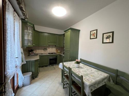 a kitchen with green cabinets and a table with chairs at Appartamento Sunflower in Viareggio