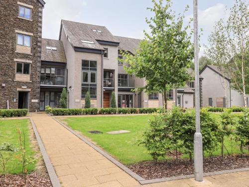 an apartment building with a lawn and a tree at Rivers Edge in Ulverston